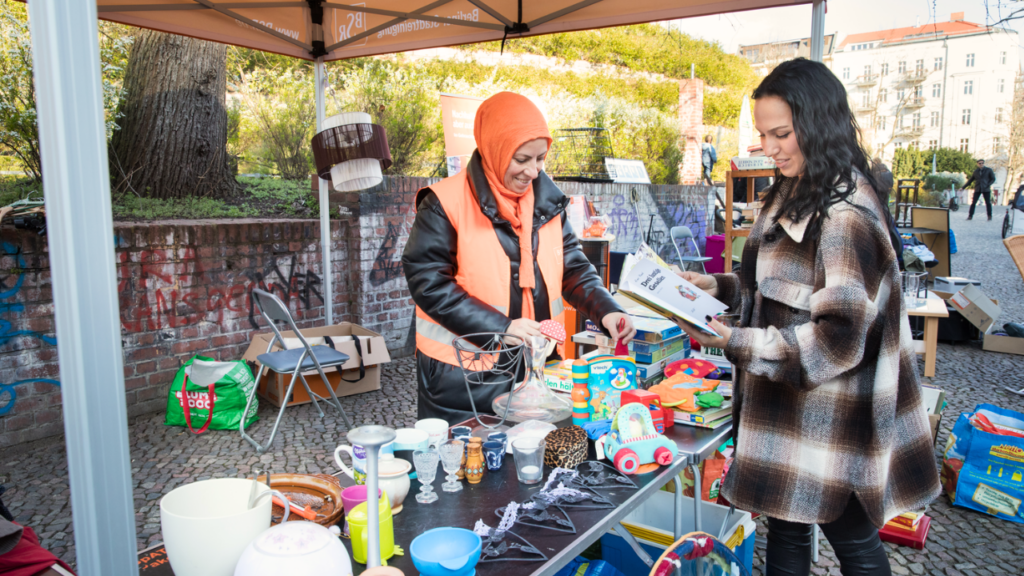 2 Frauen stehen am Stand eines Tauschmarket und tauschen gut erhaltenes Gebrauchtes