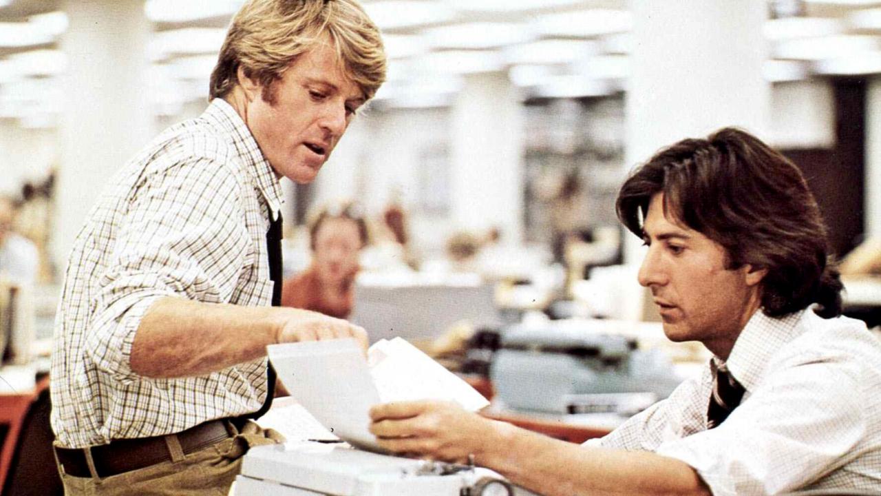 Zwei Journalisten, verkörpert von Robert redford und Dustin Hofmann sitzen im Büro und schauen sich eine Akte an.